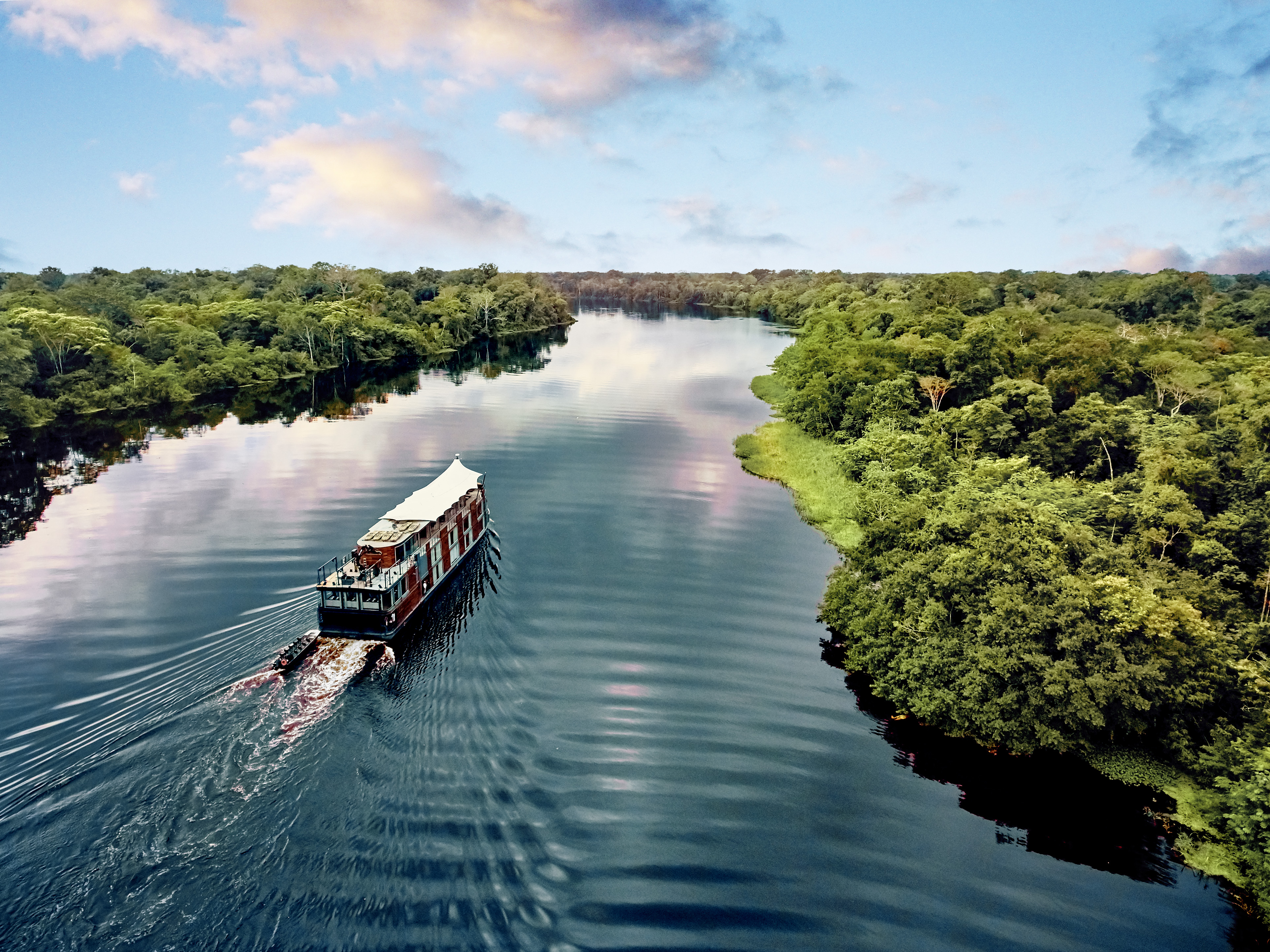 A small boat navigating the Amazon River through dense rainforest.